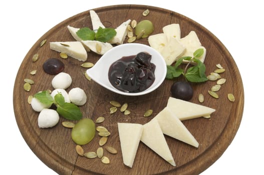 wooden plate with several varieties of cheese on a white background