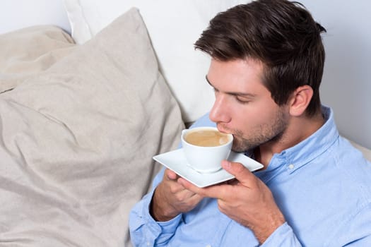 Young brunette man drinking coffee out of mug