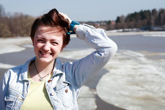 Beautiful young smiling girl on background with river and floating ice