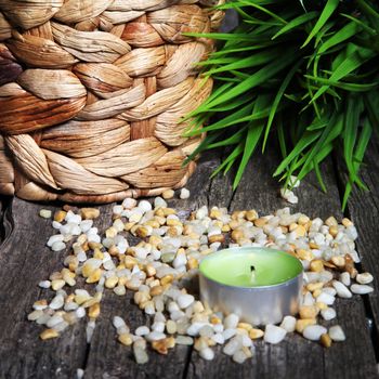 Tight composition of a beautiful small lamp with some corn like small stones and some green herbs, probably for prayer.