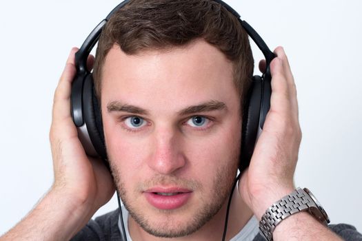 Close up of face of young man in grey t-shirt listening to music with earphones