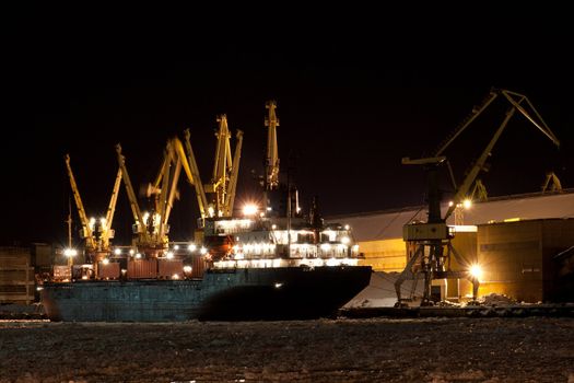 Harbor in the winter night with ship and cranes