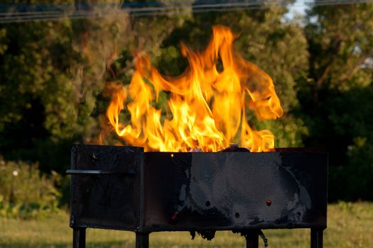 Orange flames leaping over an open empty grill outdoors