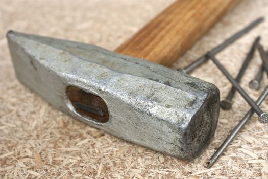 Hammer and a handful of nails are on chipboard
