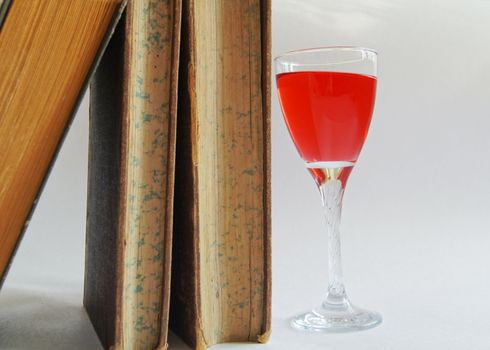 Old books and glass of rose wine
