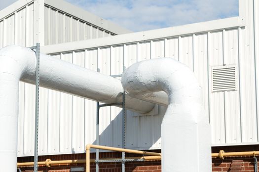 An industrial unit with a vent and large diameter air conditioning pipes.