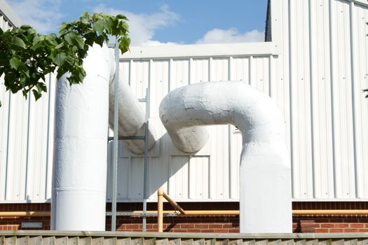 An industrial unit with a vent and large diameter air conditioning pipes.