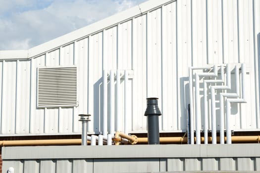 A section of an industrial unit with vent panel and a variety of piping.