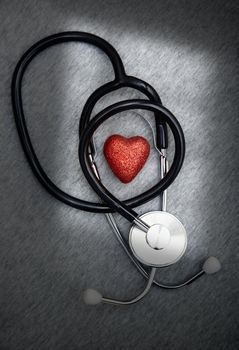 Stethoscope and heart symbol on a dark table with shadows