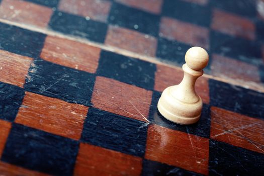 Close-up photo of the old wooden chessboard with white pawn as a symbol of the career. 