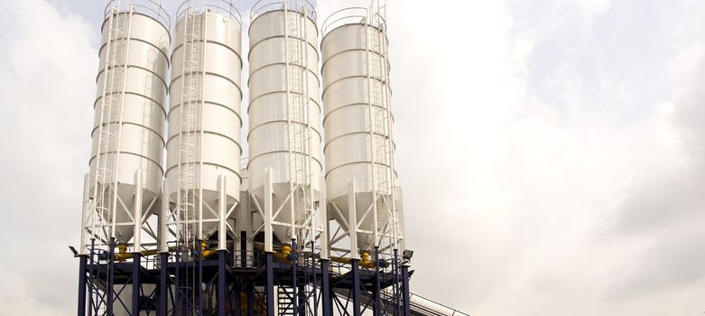A conveyor belt connected to four white silos.