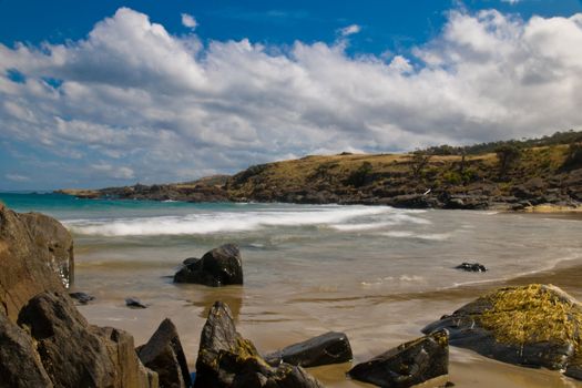 Sea landscape with bay, rock, beach, coastline, blue sky, long exposure, incoming waves