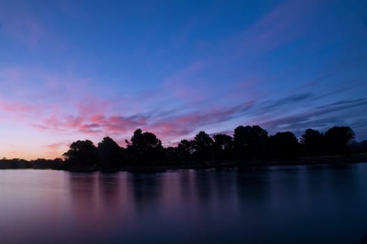 Twilight after a sunset at a beach, with long exposure, tree formation in the back ground