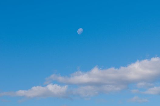 Blue clear sky with clouds and moon.