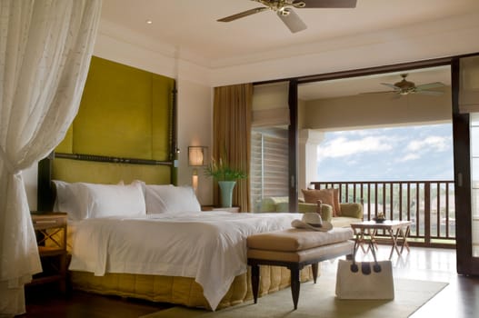 Suite bed room with balcony of a luxury resort on a sunny day