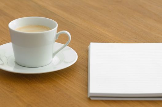 White coffee cup with note pad on a wooden table