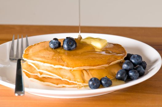 blueberry pancakes on a plate with fork on a wooden table