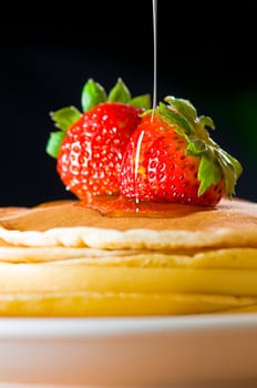 Strawberry butter pancake with honey/ maple sirup flowing down closeup shoot
