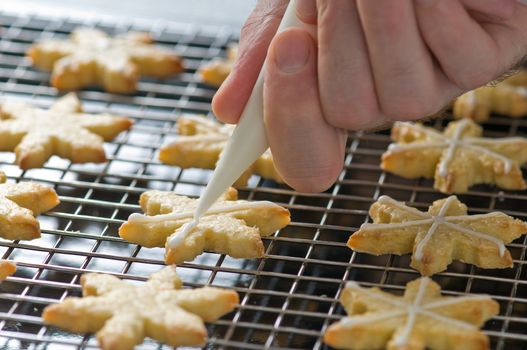 Backer decorates Christmas cookies on the backing tray with white cream