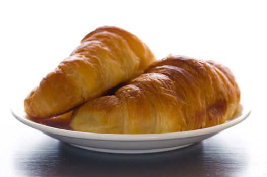 2 croissants on a plate in front of a white background
