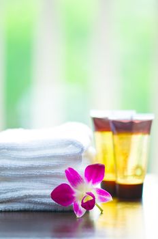 Spa towels and orchid flower in front of a white green background