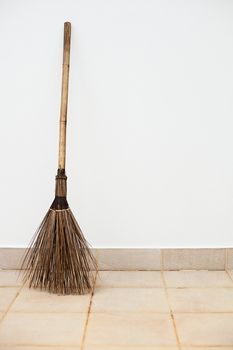 A large a broom near a white wall