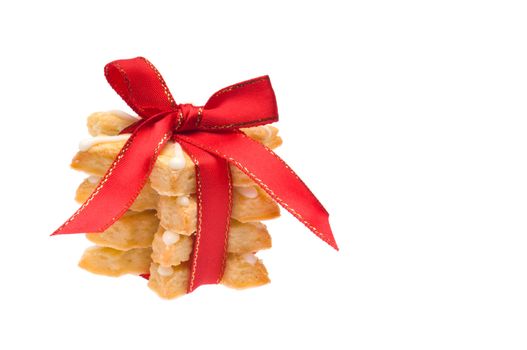 Stack of Christmas cookies wrapped in red ribbon over white