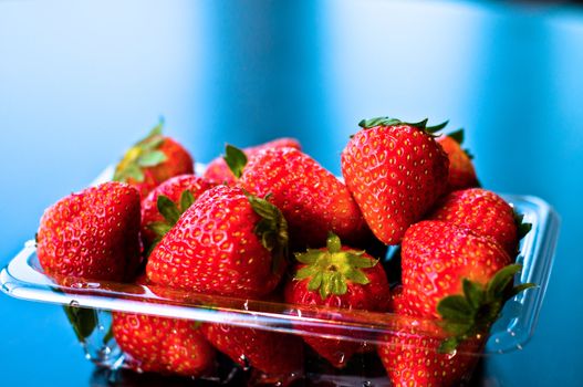 Big red strawberries in a plastic sale box 