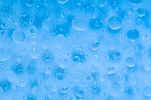 Water drops on a shiny surface in light blue