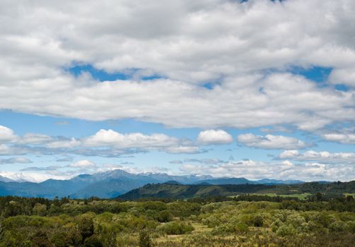 Massive cloudy sky above the wilderness with mountain range in the background 