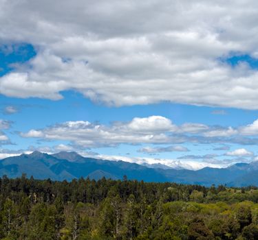 Massive cloudy sky above the wilderness with mountain range in the background