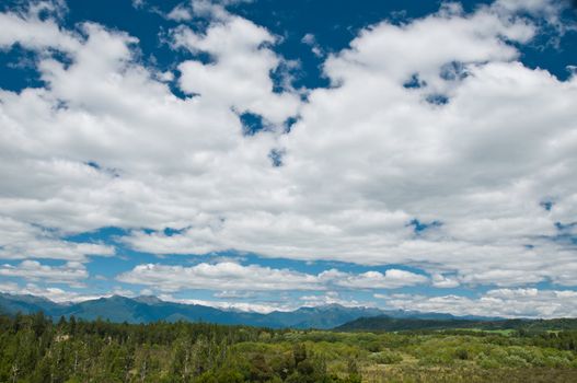 Massive cloudy sky above the wilderness with mountain range in the background
