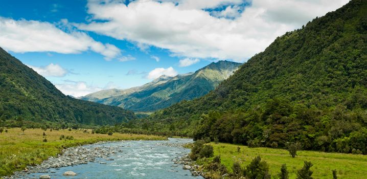 river flowing through a valley with mountain massive in the back ground