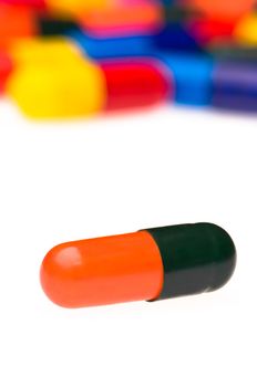 One orange black capsule in front of many colorful, blurry in the background