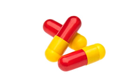 Three red yellow capsules over white two as a stack