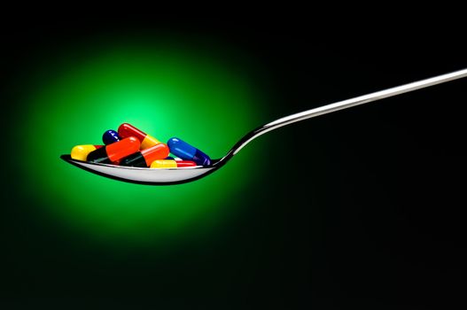 One spoon of medication in front of a black background