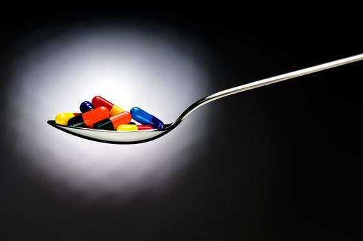 One spoon of medication in front of a black background