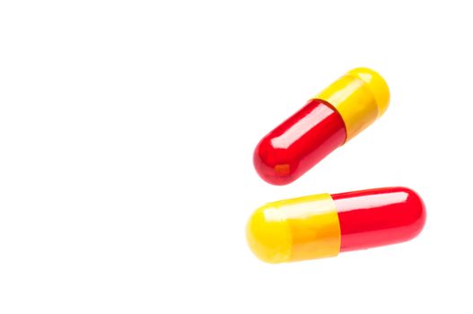 Two yellow red capsules over white