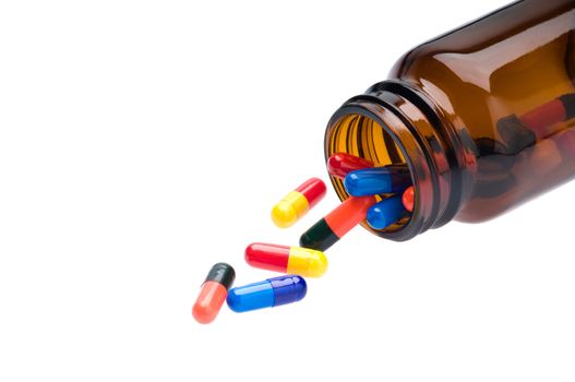 Open pharmaceutical bottle which spills colored capsules over white