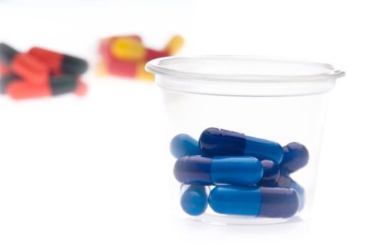 Colorful tablets, capsules in a container, over white 