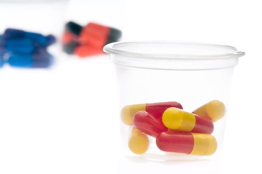 Colorful tablets, capsules in a container, over white 