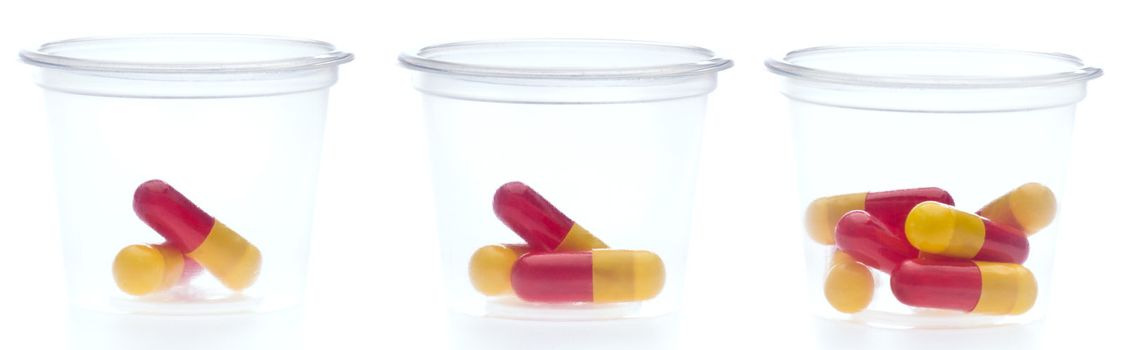 Three containers with different amount of pills, over white