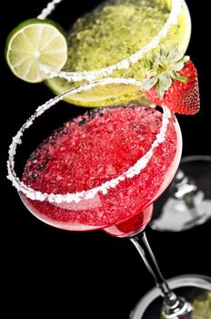 One Classic and a Strawberry Margarita in front of a black background with fresh garnish