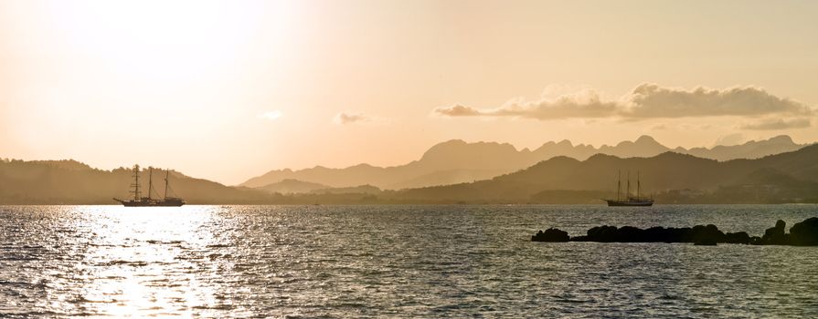 sailboat bathed in dawn sunlight whereby the sun produces nice reflection in the ocean