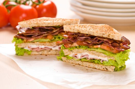 Two sandwich on wrapping paper back ground has tomatoes and dishware