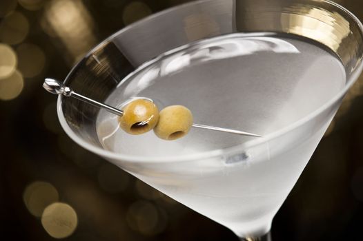 Vodka Martini with olive garnish in front of a gold glitter background