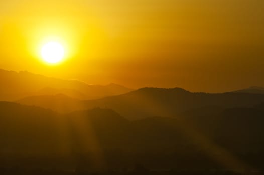 Sunset behind mountains with golden color