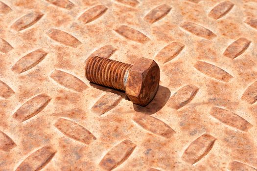 Grungy background with a rusty ridged metal plate and old hexagonal bolt