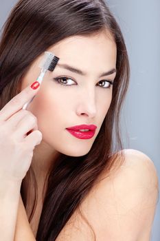 Pretty young woman combing her eyebrow