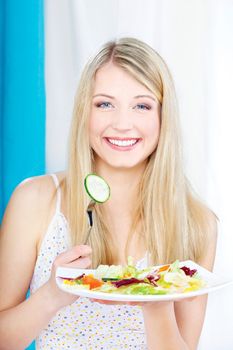 Pretty girl holding salad on fork and plate